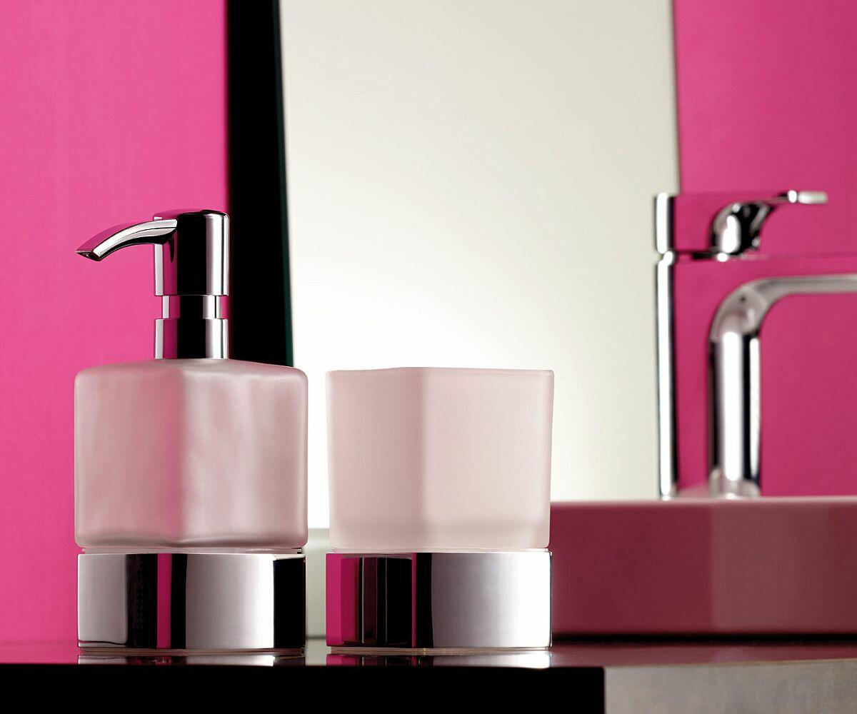 Mundspülglas und Flüssigseifenspender vor rosa Wand